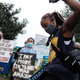 A woman holds up her phone in front of protesters holding signs speaking up against Amazon.
